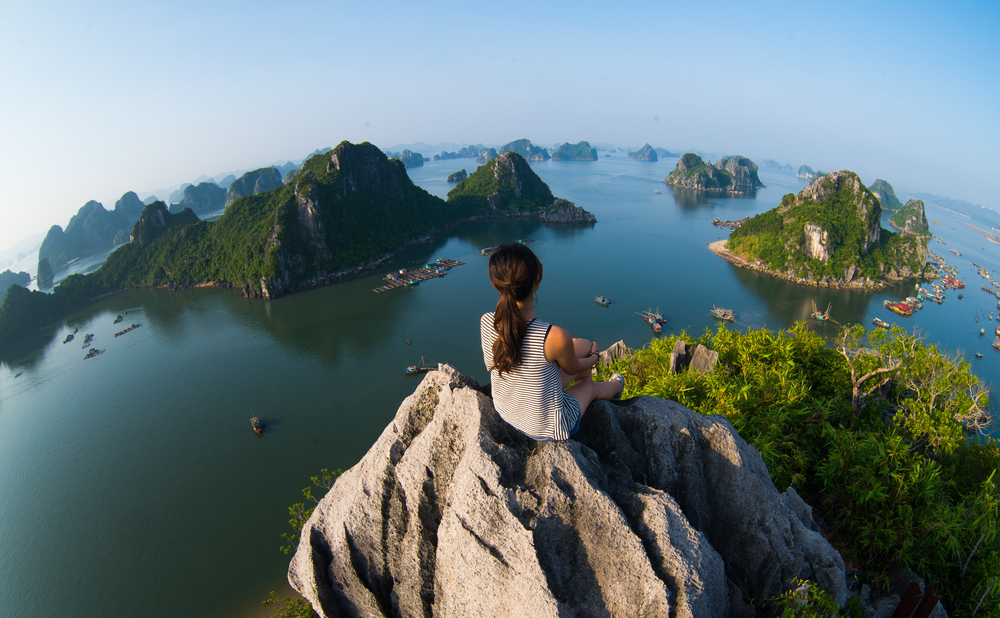 Woman sits on rock surrounded by foreign islands.