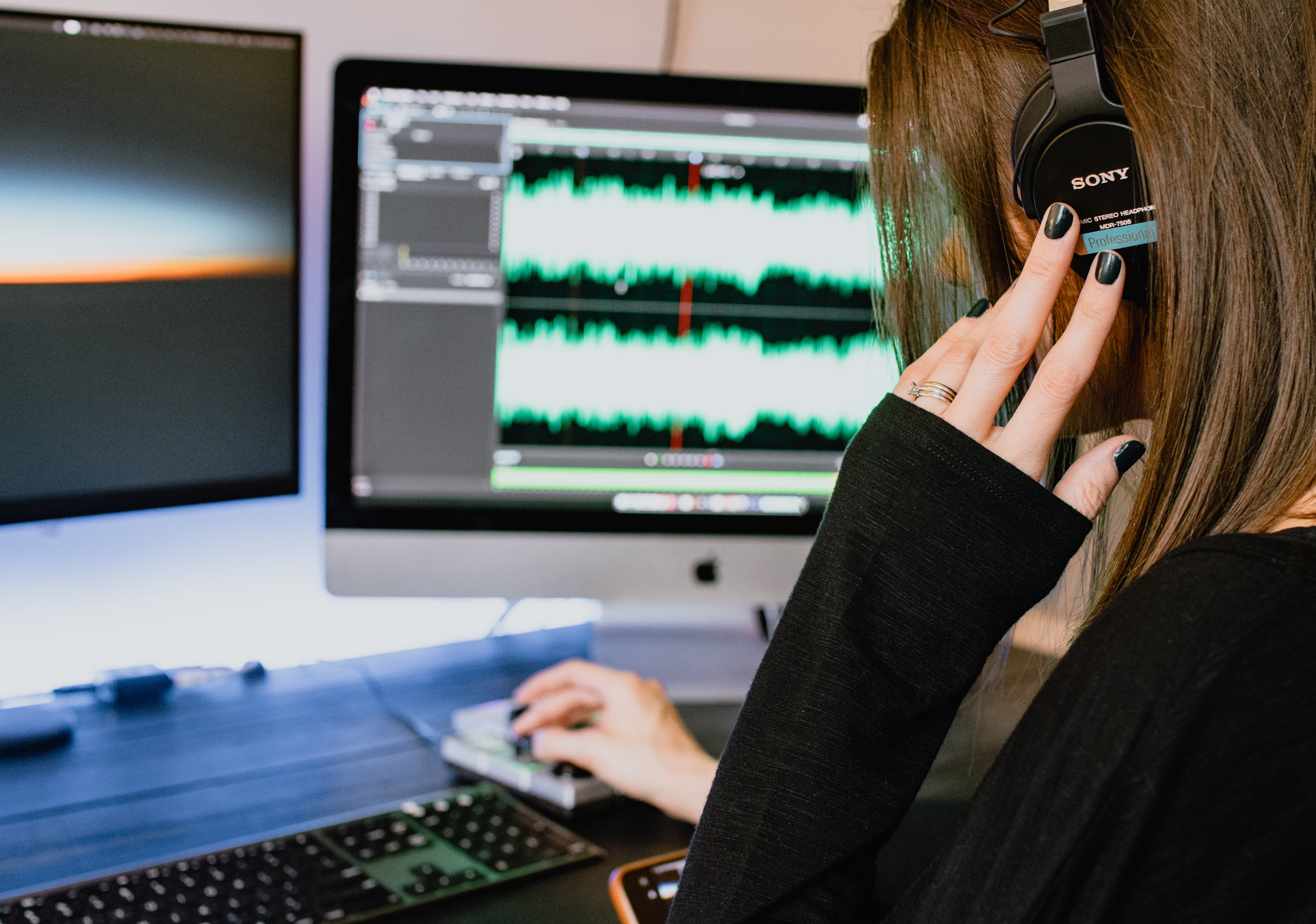 Woman at computer editing sound for music licensing