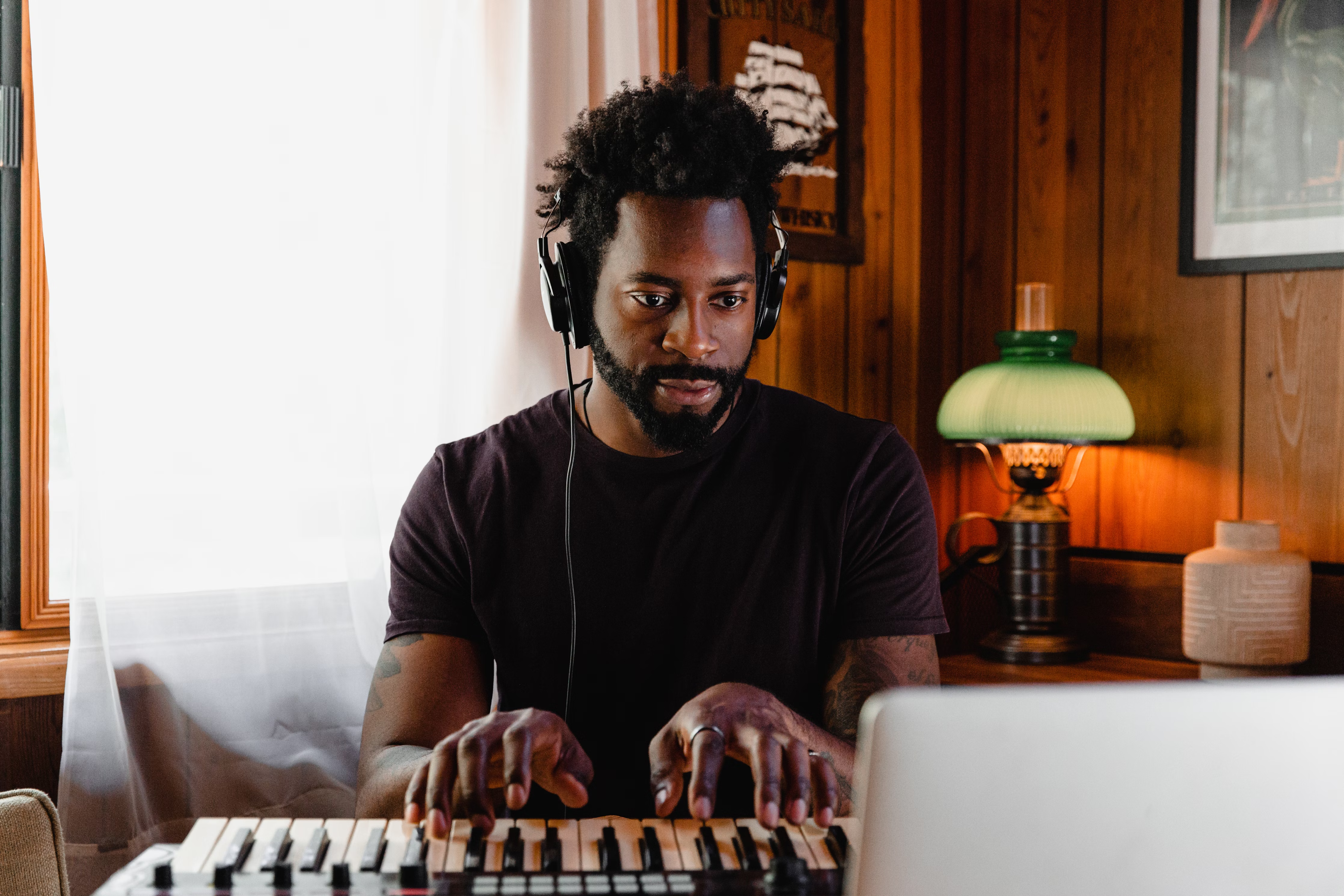 Man with headphones at an electric piano creating his music master recordings